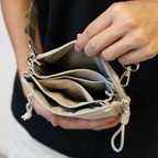 Person holding a beige crossbody bag with multiple compartments.