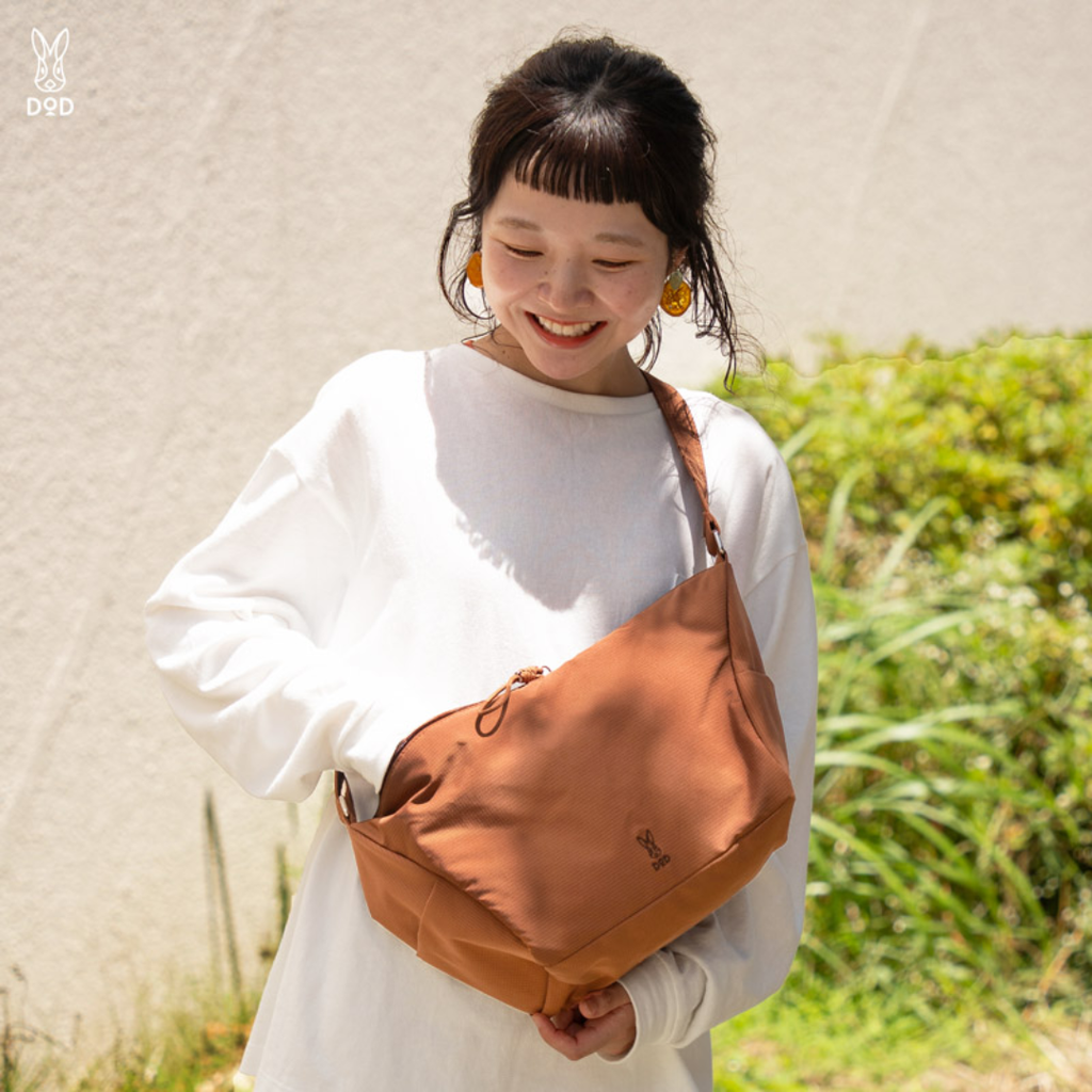 Woman holding a brown bag outdoors with a blurred background